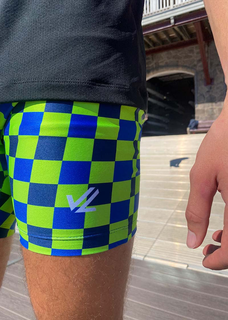 JL Racing green and blue checkered trou shorts holding a oar.