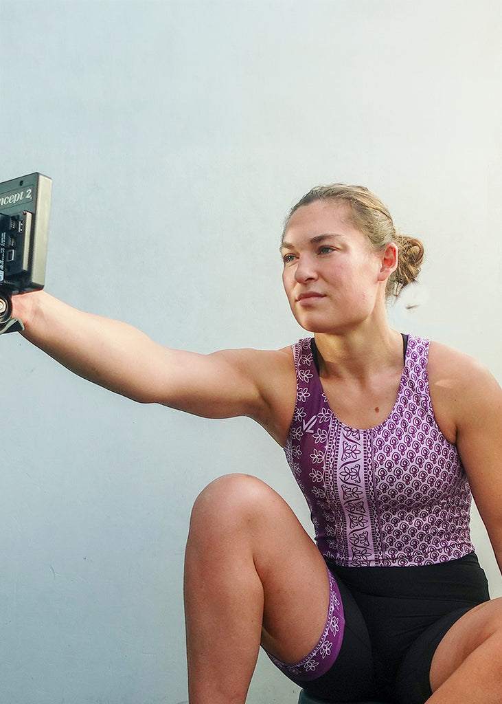 Woman wearing a JL Lavender Launch Unisuit on a rowing machine