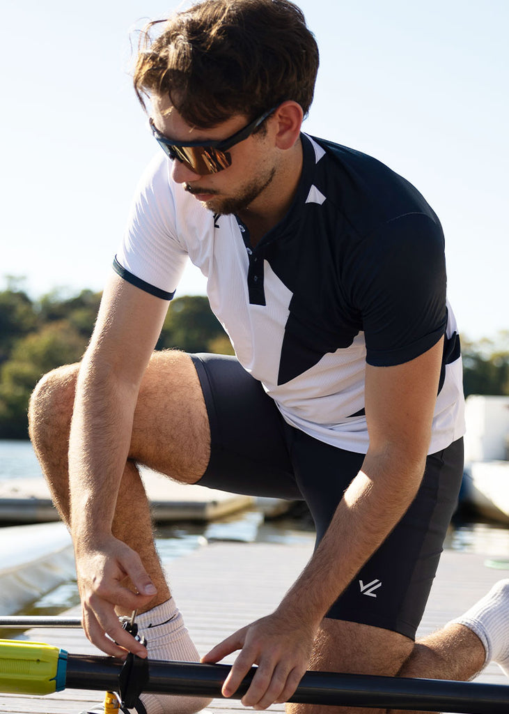 Man in JL Legacy Star Henley adjusting a rowing boat on a dock with a scenic background