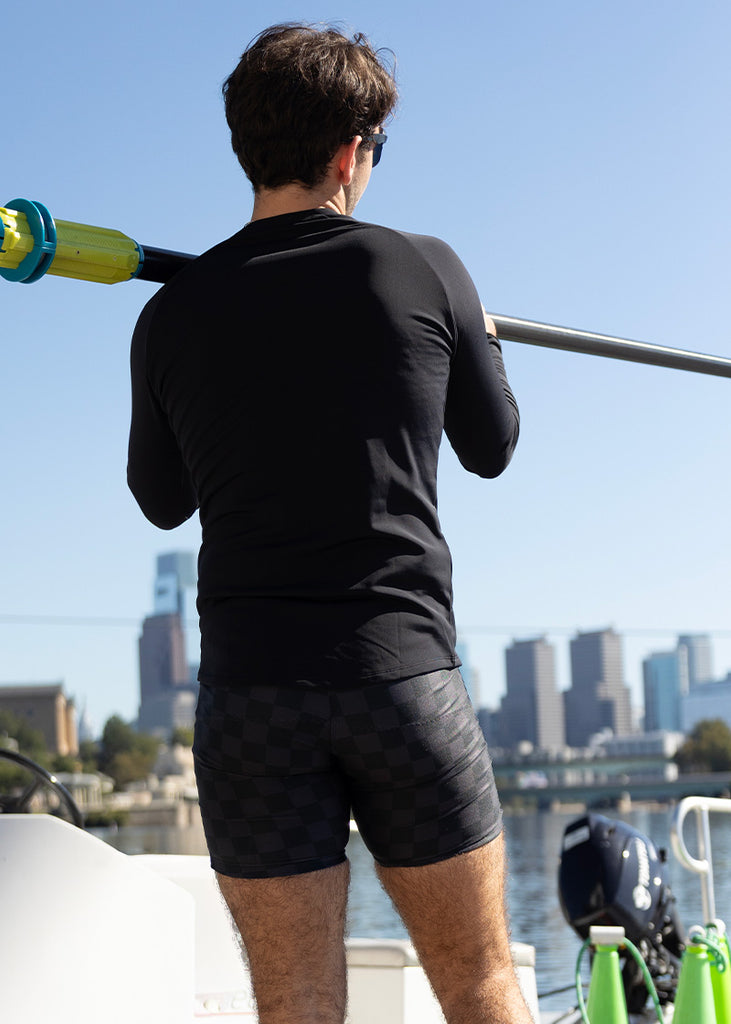 JL Racing Mode holding a paddle with a cityscape in the background wearing unixex checkered trou or shorts
