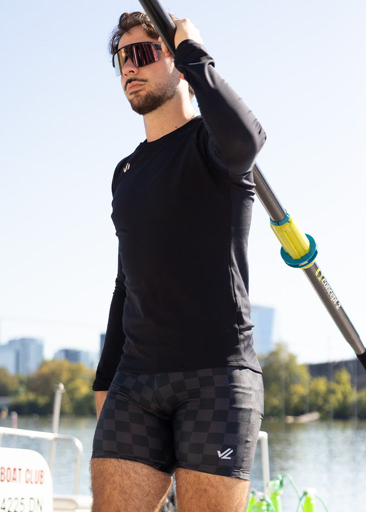 JL Racing Mode holding a paddle with a cityscape in the background wearing unixex checkered trou or shorts